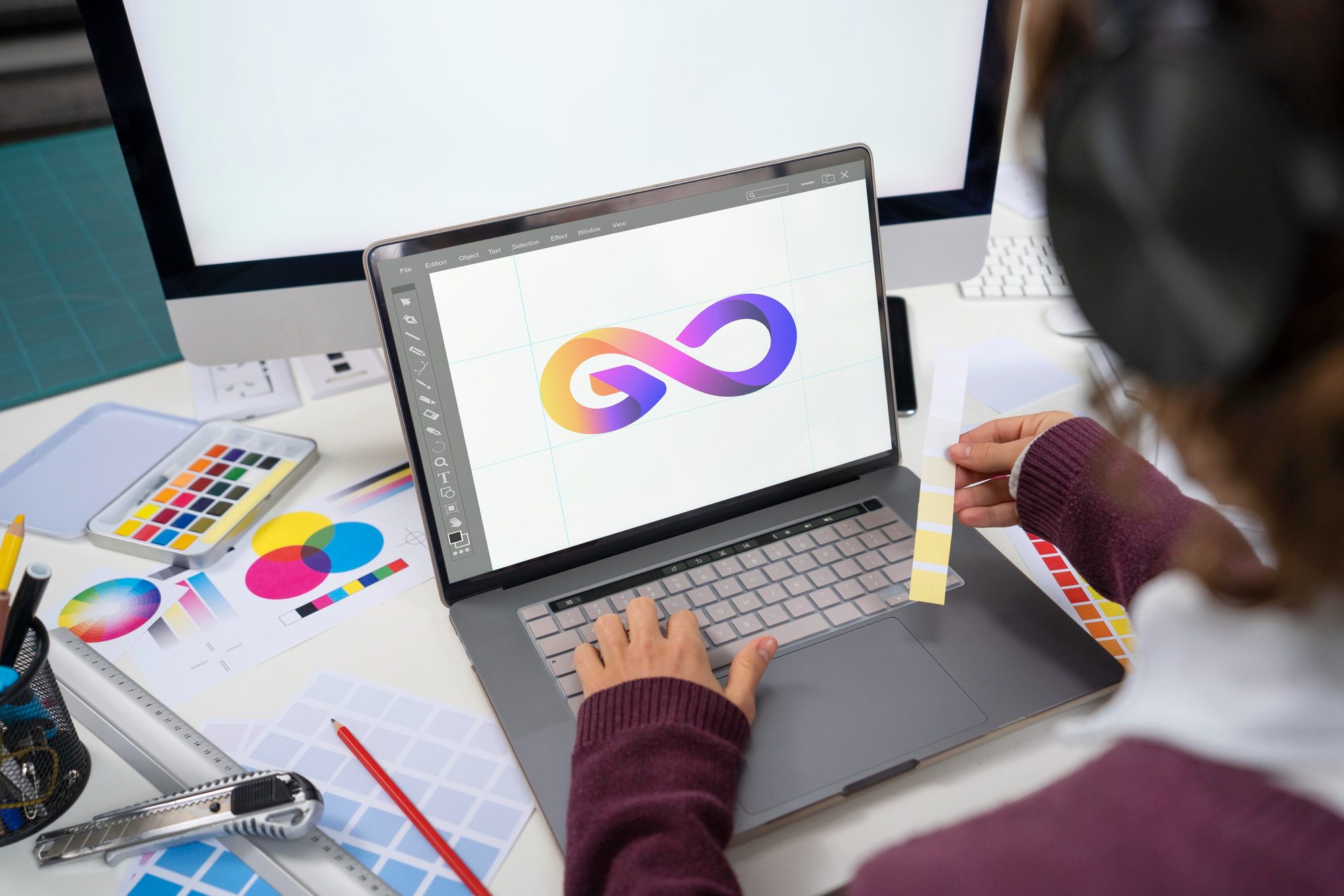 Person working on graphic design of colorful infinity logo on a laptop.